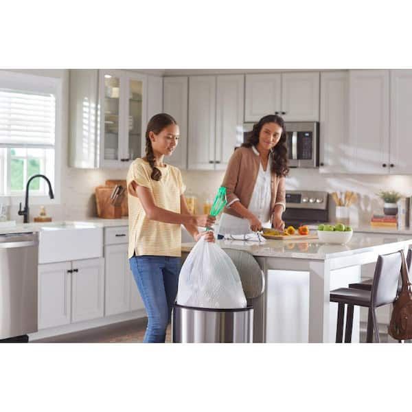 Två kvinnor i ett kök, en tar ut en soppåse ur en papperskorg.